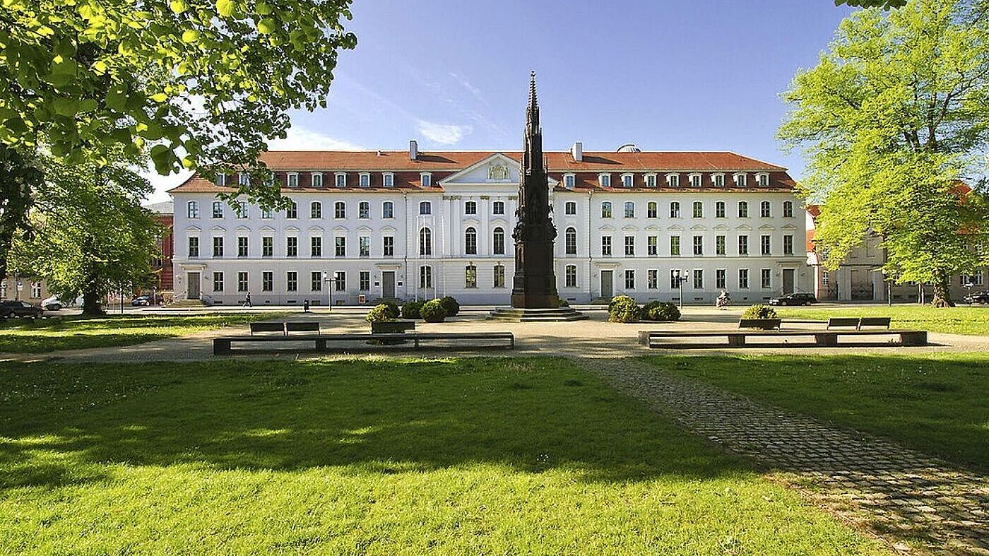 Das Hauptgebäude der Universität Greifswald im Sonnenschein mit blauem Himmel