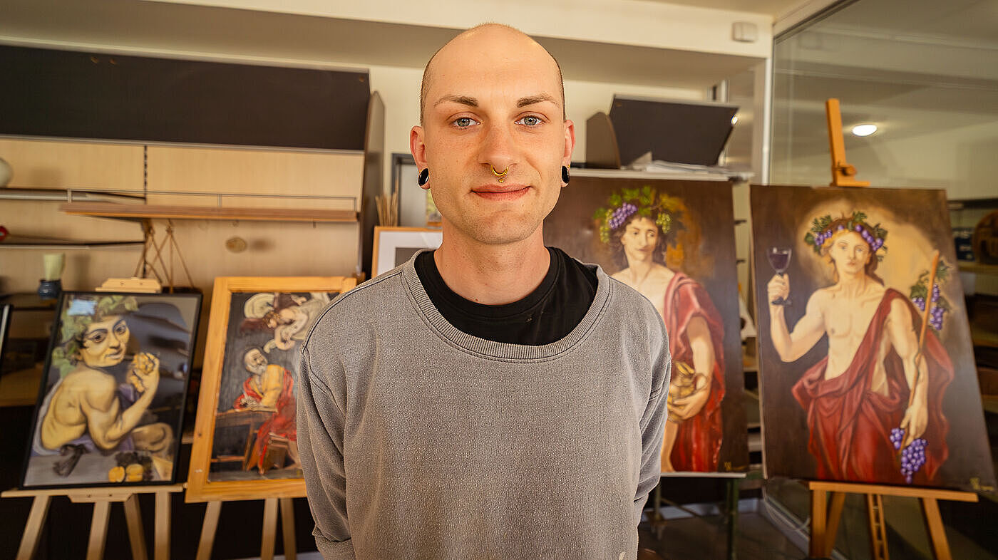 Lukas Schallon in den Kleinwachauer Werkstatt in Radeberg. Dahinter sind Gemälde von ihm zu sehen, Götter aus der griechischen Mythologie