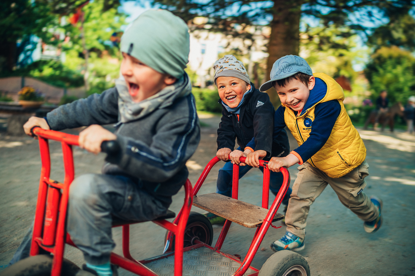 Drei Jungen spielen mit einem roten Fahrzeug in den Außenanlagen der Kita Schatzinsel in Pulsnitz in Sachsen. Die Kita Schatzinsel gehört zum Epilepsiezentrum Kleinwachau in Radeberg.