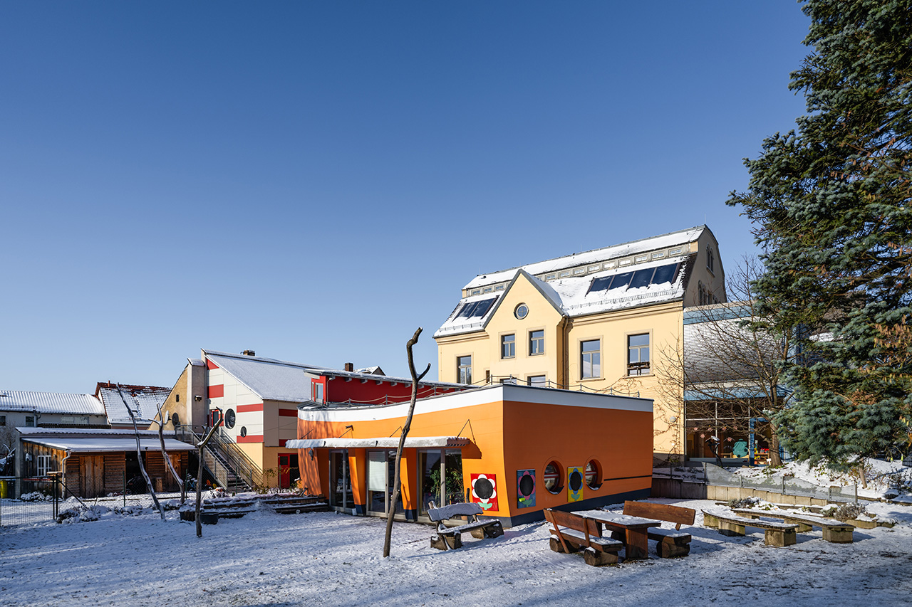 Blick auf drei Gebäude, eines sieht aus wie eine Arche, es liegt Schnee