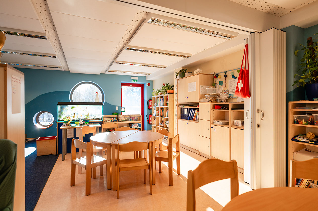Blick in einen Raum der Kita, dort stehen einige Stühle und ein Tisch